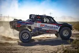 A BFGoodrich trophy truck catching air while racing in the desert.