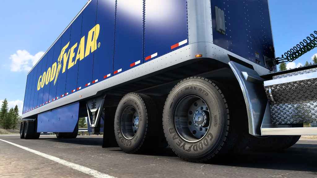 A blue Goodyear tractor-trailer on the highway showing its commercial trailer tires.