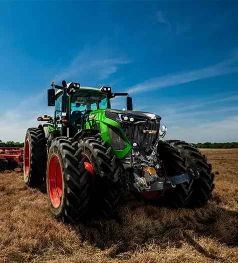 A large green farm tractor in a field, equipped with durable Mastercraft agricultural tires.