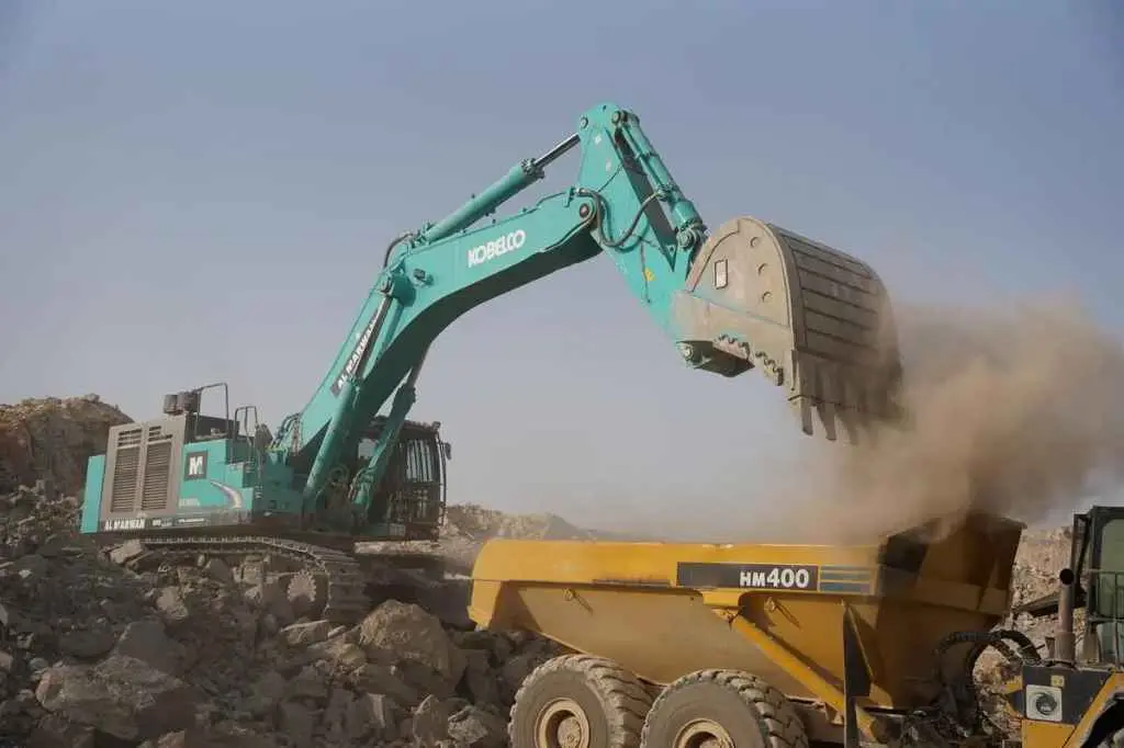 An excavator loading a dump truck at a worksite, an application for durable Sumitomo OTR tires.