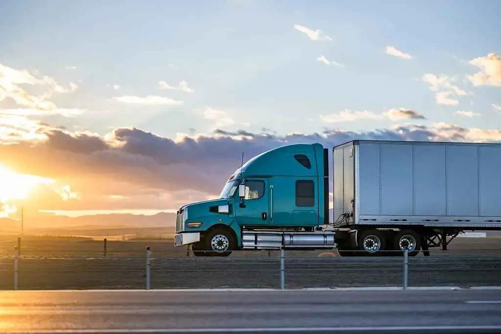A modern long-haul commercial truck driving on the highway at sunset, equipped with reliable Supermax tires.