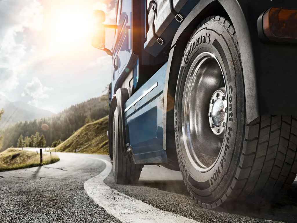 A close-up of a Continental Conti Hybrid HD3 commercial truck tire as the truck drives on a mountain road.